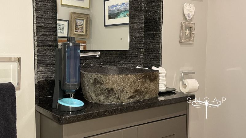 SNOAP refillable soap dispenser releasing powdered soap into hands before washing.